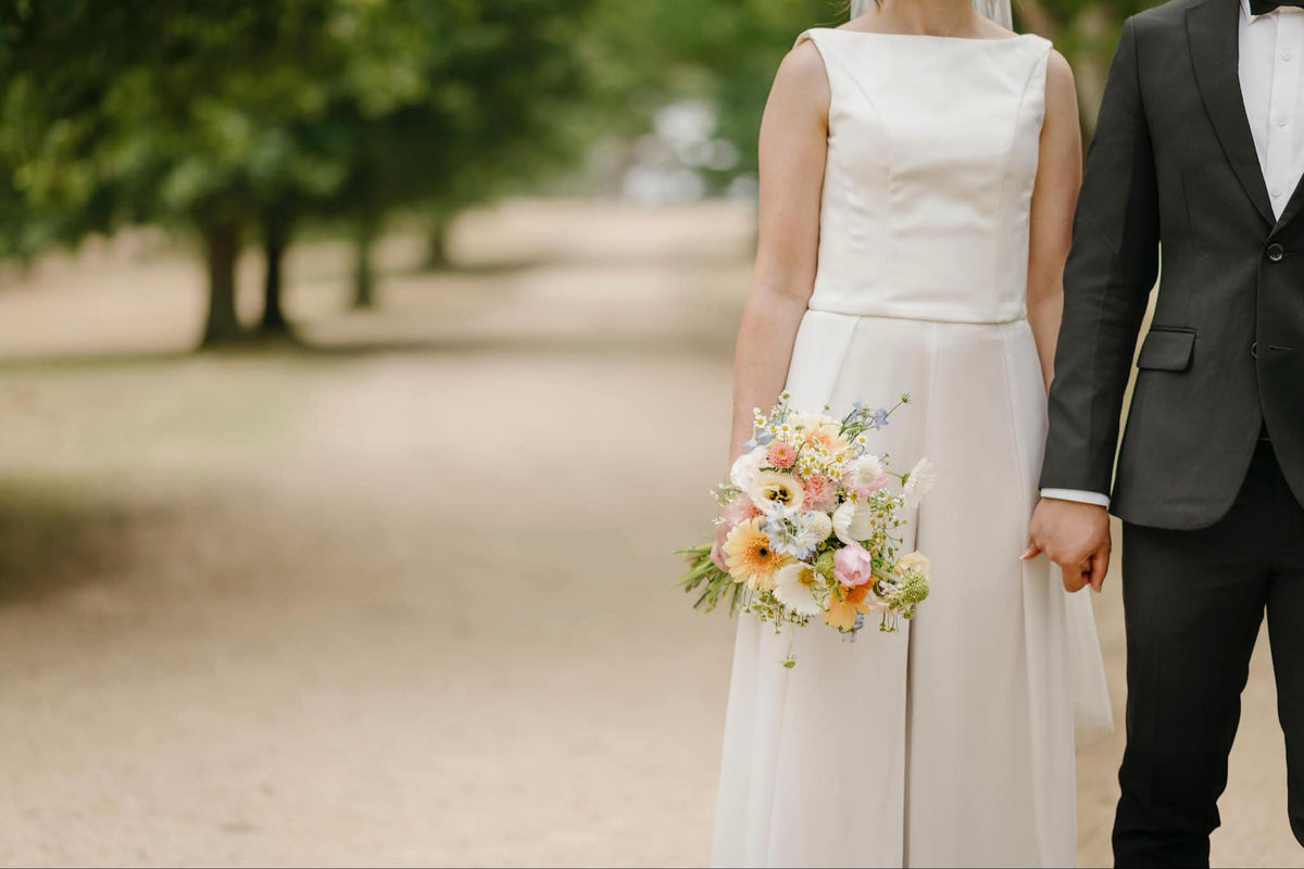 Couple holding hands with a bouquet in a park setting